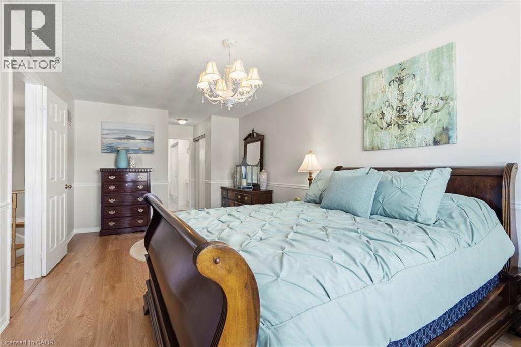 Bedroom with a closet, light wood-style floors, hanging lights, and a textured ceiling - 18 Webster Way, Georgetown, ON - Indoor Photo Showing Bedroom