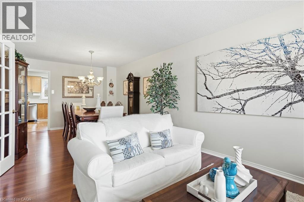 Living room with wood finished floors, suspended lighting, and a textured ceiling - 18 Webster Way, Georgetown, ON - Indoor Photo Showing Living Room