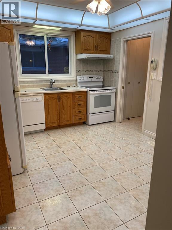 Kitchen featuring wood cabinetry, white appliances, and tiled flooring - 21 Bluebird Avenue, Hamilton, ON