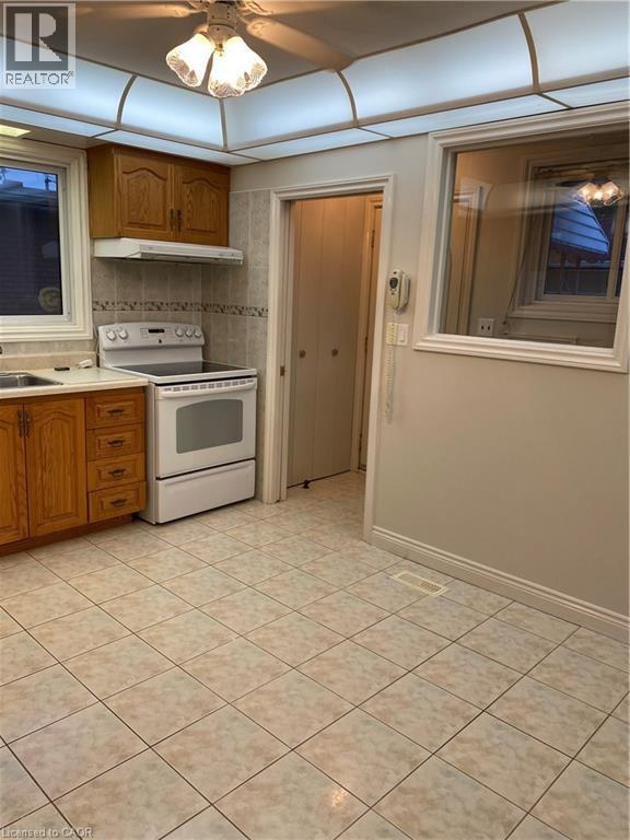 Kitchen featuring wood cabinetry, white appliances, tile flooring, and a drop ceiling with integrated lighting - 21 Bluebird Avenue, Hamilton, ON