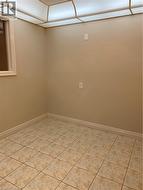 Room featuring neutral-toned walls, square tile flooring, a window with white trim, and a ceiling-mounted light fixture -