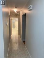 Hallway with square tile flooring, light-toned walls, and white trim -