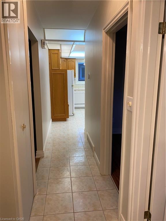 Hallway with light-colored square floor tiles and neutral wall tones - 21 Bluebird Avenue, Hamilton, ON