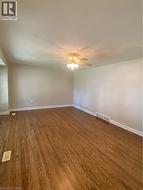 Expansive room featuring rich wood-finish flooring, light neutral-toned walls, and a ceiling fan with integrated lighting -