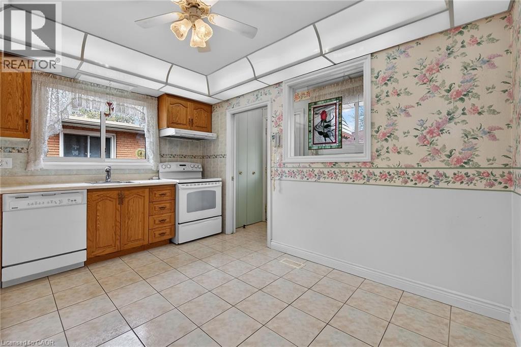 Kitchen featuring wood finish cabinetry, white appliances, ceiling fan, light countertops, and wallpapered walls - 21 Bluebird Avenue, Hamilton, ON - Indoor Photo Showing Kitchen