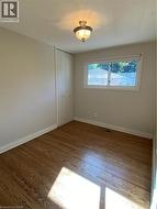 Light-filled room featuring hardwood flooring, a white-framed window, and a built-in closet with bifold doors -