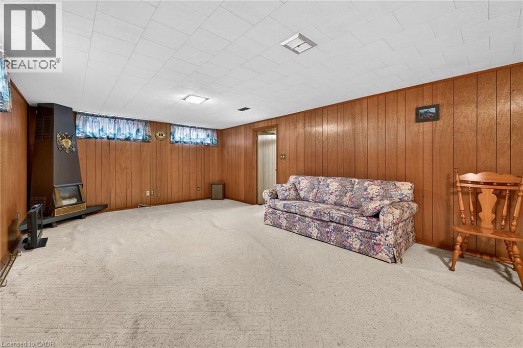 Living area with carpet flooring and wooden walls - 21 Bluebird Avenue, Hamilton, ON