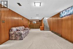 Living area featuring a baseboard radiator, wooden walls, and light carpet -