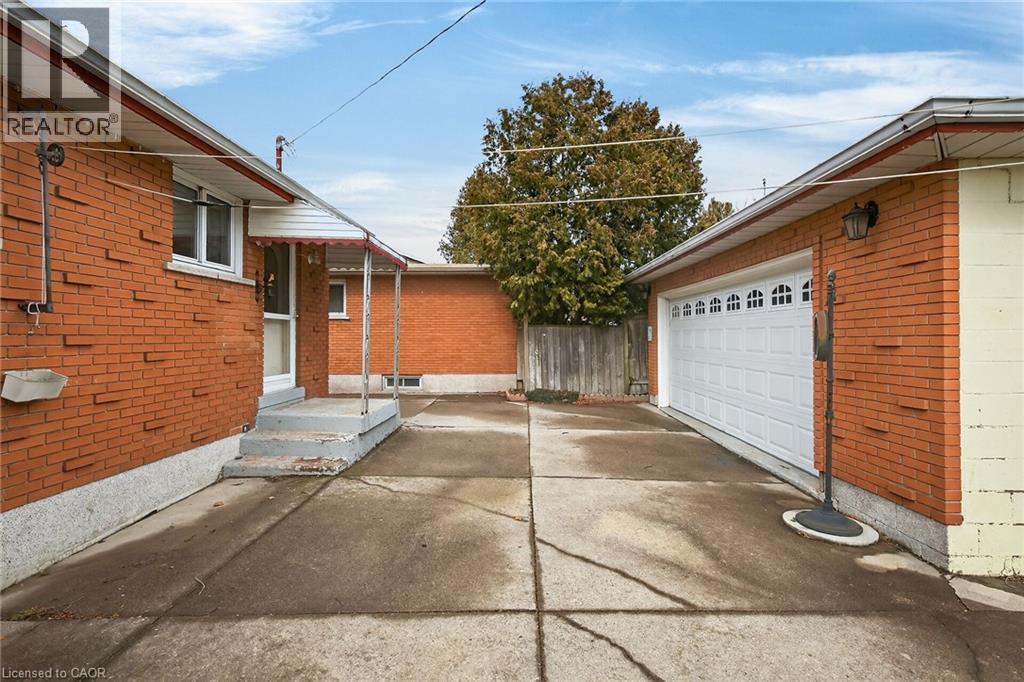 View of home's exterior with an outbuilding, brick siding, and a garage - 21 Bluebird Avenue, Hamilton, ON
