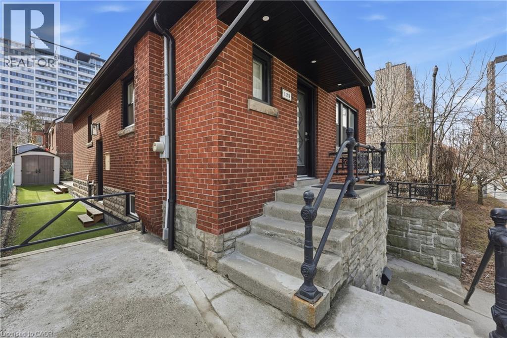View of property exterior featuring brick siding and a shed - 129 Jackson Street W, Hamilton, ON - Outdoor
