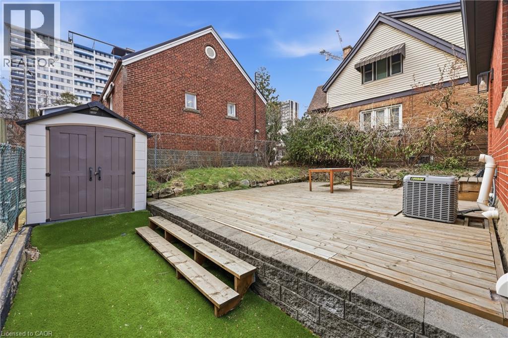 Wooden terrace featuring a shed, a fenced backyard, and a patio area - 129 Jackson Street W, Hamilton, ON - Outdoor With Exterior