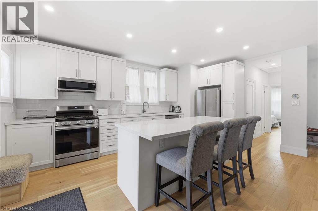 Kitchen with stainless steel appliances, a center island, white cabinets, a kitchen bar, and backsplash - 129 Jackson Street W, Hamilton, ON - Indoor Photo Showing Kitchen With Stainless Steel Kitchen With Upgraded Kitchen