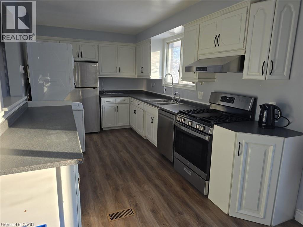 Kitchen featuring stainless steel appliances, white cabinets, dark countertops, and exhaust hood - 593 Mount Anne Drive, Waterloo, ON - Indoor Photo Showing Kitchen With Double Sink