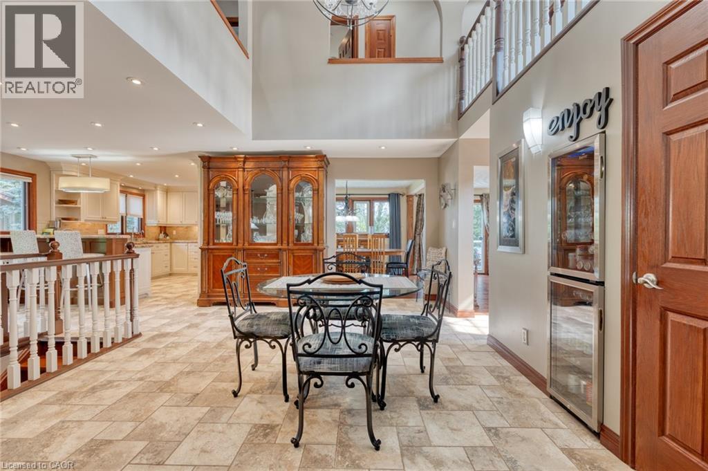 Dining space featuring light stone finish flooring, a high ceiling, beverage cooler, and a chandelier - 15 Marquette Drive, Kitchener, ON - Indoor Photo Showing Dining Room