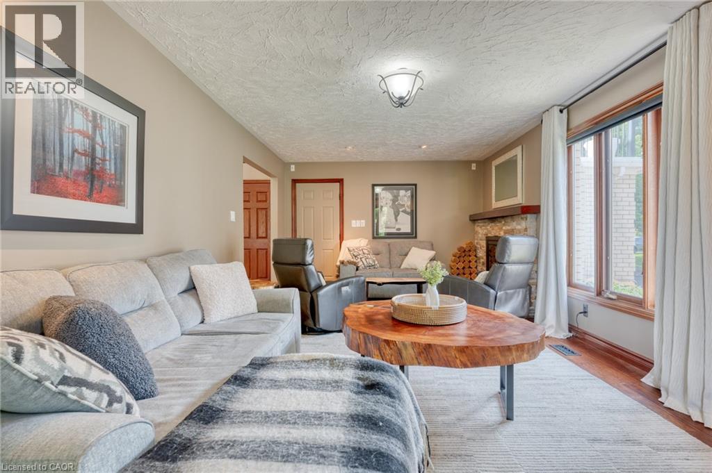 Living room featuring wood finished floors, a textured ceiling, and a fireplace - 15 Marquette Drive, Kitchener, ON - Indoor