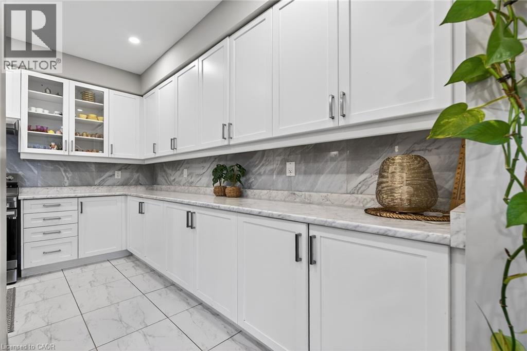 Kitchen featuring light marble finish flooring, white cabinets, glass insert cabinets, decorative backsplash, and recessed lighting - 7809 Hackberry Trail E, Niagara Falls, ON - Indoor Photo Showing Kitchen