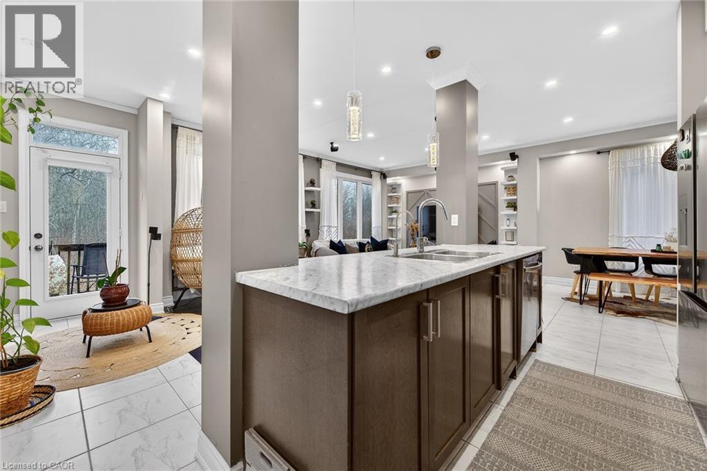 Kitchen with dark wood finish cabinetry, pendant lighting, open floor plan, a kitchen island with sink, and stainless steel fridge - 7809 Hackberry Trail E, Niagara Falls, ON - Indoor Photo Showing Kitchen With Upgraded Kitchen