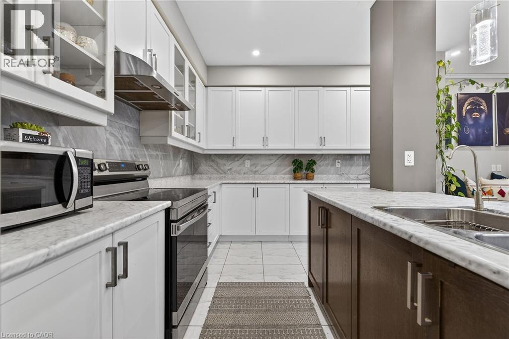 Kitchen with stainless steel appliances, glass insert cabinets, two tone cabinets, exhaust hood, and decorative backsplash - 7809 Hackberry Trail E, Niagara Falls, ON - Indoor Photo Showing Kitchen With Upgraded Kitchen