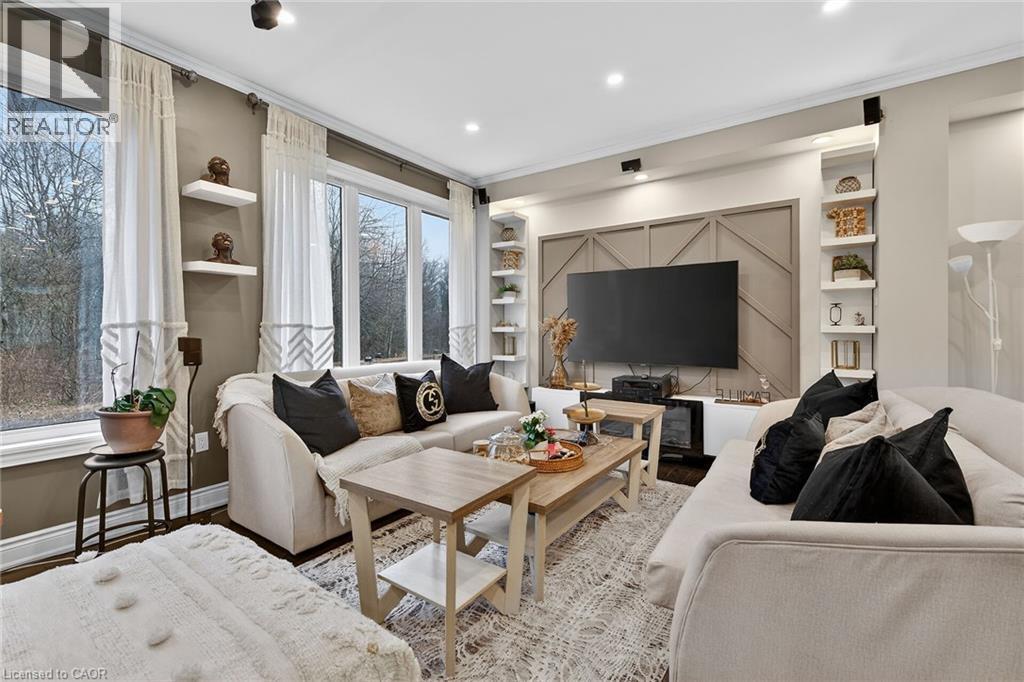 Living room with built in shelves, wood finished floors, ornamental molding, and recessed lighting - 7809 Hackberry Trail E, Niagara Falls, ON - Indoor Photo Showing Living Room