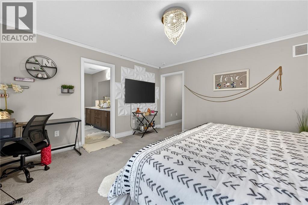 Bedroom featuring a desk, light carpet, ornamental molding, and connected bathroom - 7809 Hackberry Trail E, Niagara Falls, ON - Indoor Photo Showing Bedroom