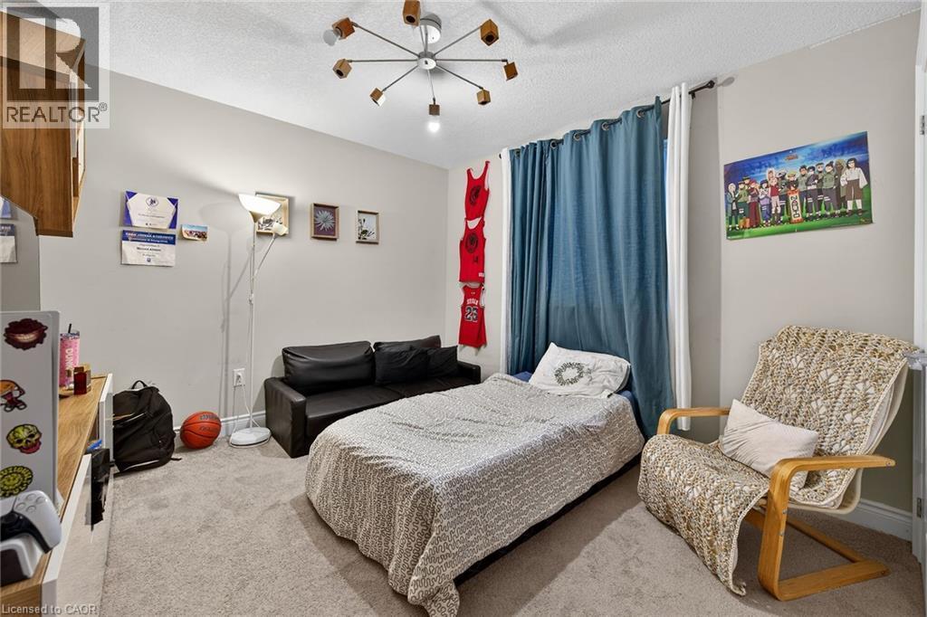 Carpeted bedroom featuring a textured ceiling and a chandelier - 7809 Hackberry Trail E, Niagara Falls, ON - Indoor Photo Showing Bedroom