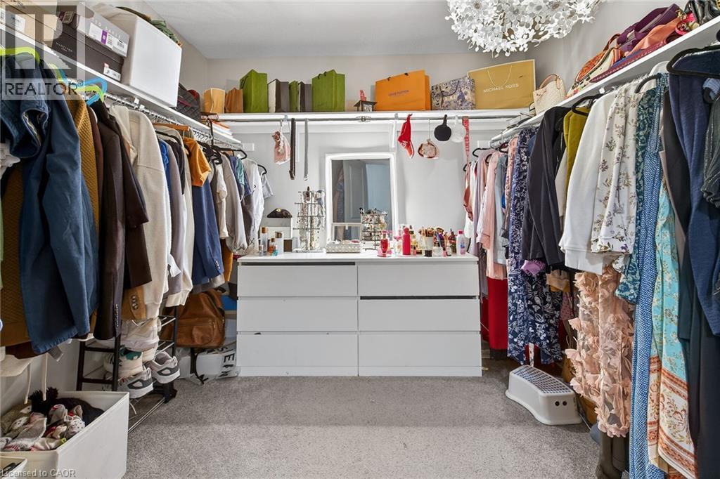 Walk in closet with light colored carpet and hanging lights - 7809 Hackberry Trail E, Niagara Falls, ON - Indoor With Storage