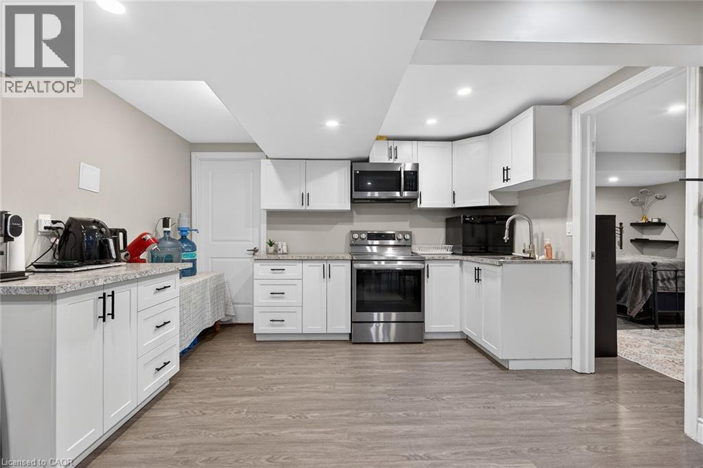 Kitchen featuring white cabinetry, stainless steel appliances, light wood finished floors, light stone countertops, and recessed lighting - 7809 Hackberry Trail E, Niagara Falls, ON - Indoor Photo Showing Kitchen