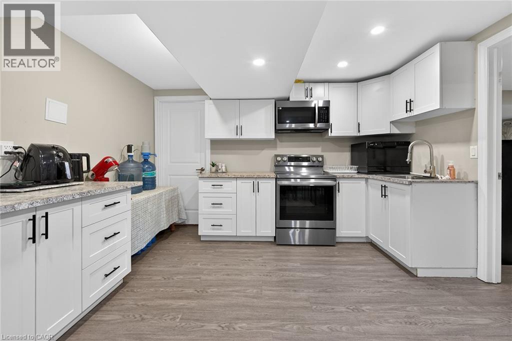 Kitchen with white cabinets, stainless steel appliances, light wood finished floors, light stone countertops, and recessed lighting - 7809 Hackberry Trail E, Niagara Falls, ON - Indoor Photo Showing Kitchen