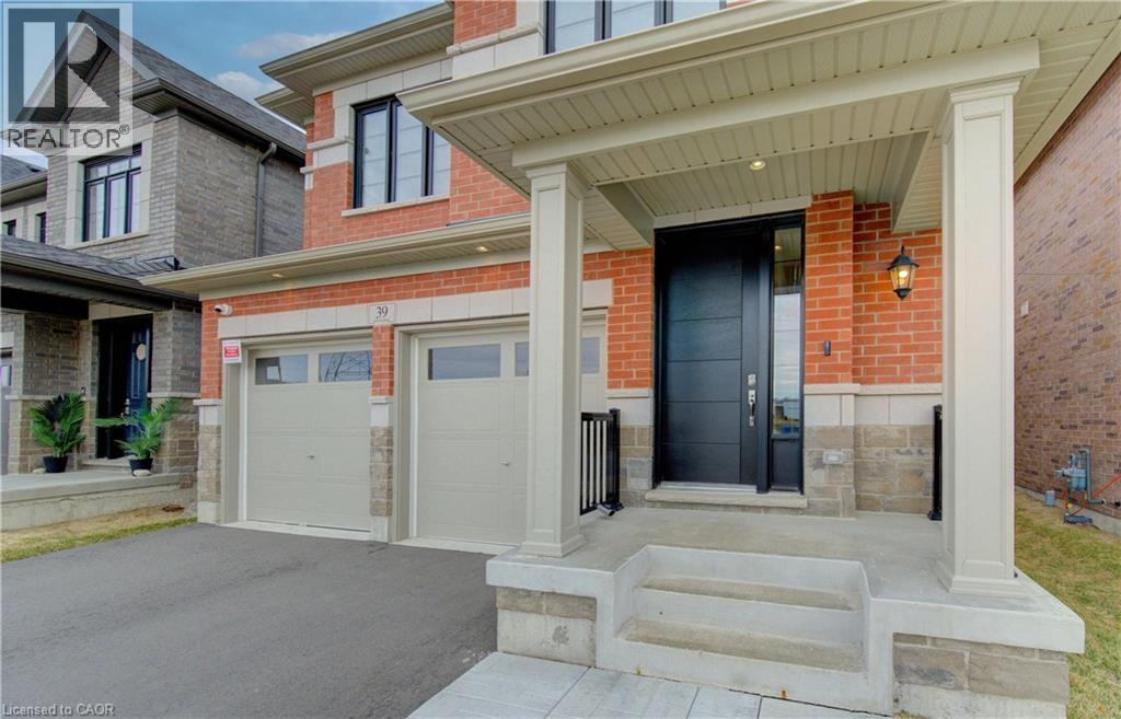 View of exterior entry featuring a porch, asphalt driveway, brick siding, and a garage - 39 Guernsey Drive, Kitchener, ON - Outdoor