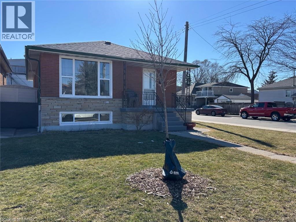 View of front of home featuring a front yard, stone siding, brick siding, and roof with shingles - 1224 Dunsmure Road, Hamilton, ON - Outdoor