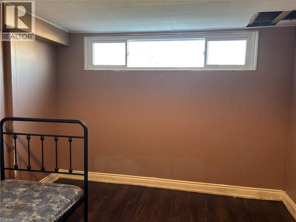 Unfurnished bedroom featuring dark wood-style floors and multiple windows - 1224 Dunsmure Road, Hamilton, ON - Indoor Photo Showing Other Room