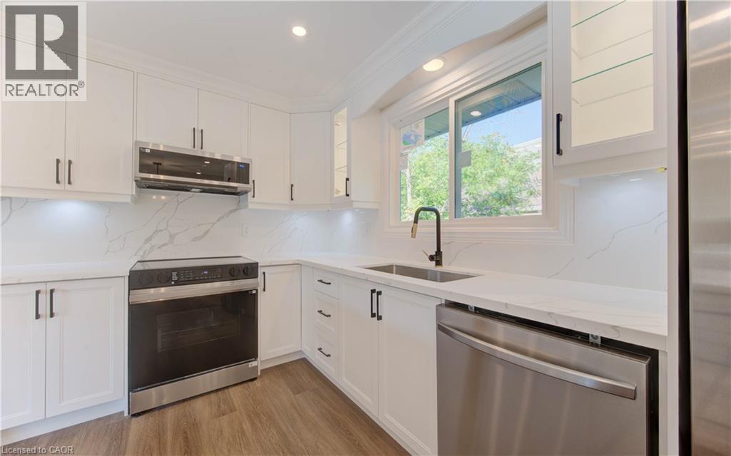 Kitchen with stainless steel appliances, backsplash, ornamental molding, white cabinets, and light wood-style flooring - 90 Culpepper Drive, Waterloo, ON - Indoor Photo Showing Kitchen With Upgraded Kitchen