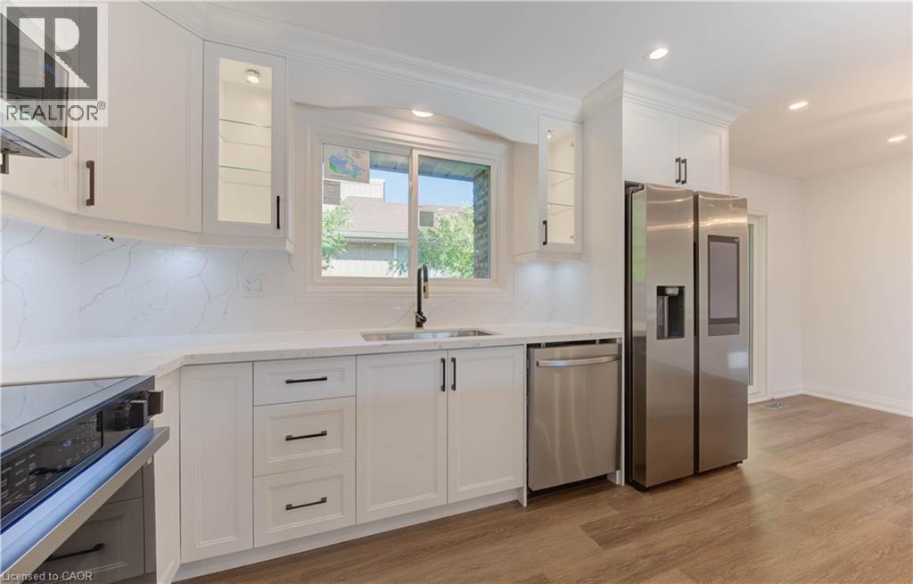 Kitchen featuring stainless steel appliances, glass insert cabinets, white cabinetry, light wood-style flooring, and recessed lighting - 90 Culpepper Drive, Waterloo, ON - Indoor Photo Showing Kitchen With Upgraded Kitchen