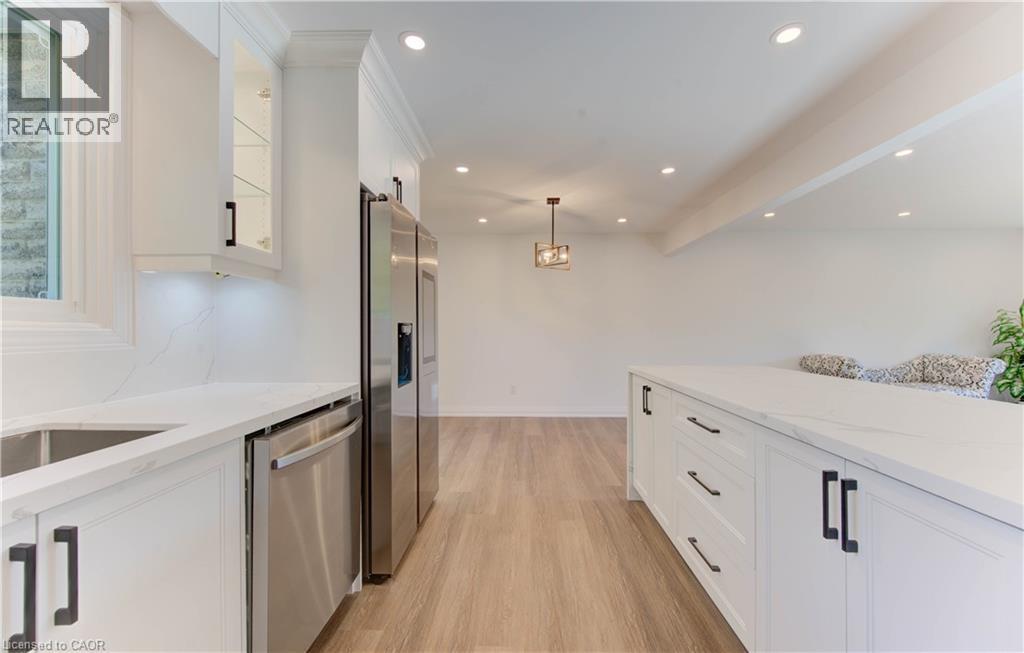 Kitchen featuring white cabinets, light stone countertops, decorative light fixtures, appliances with stainless steel finishes, and recessed lighting - 90 Culpepper Drive, Waterloo, ON - Indoor Photo Showing Kitchen With Upgraded Kitchen