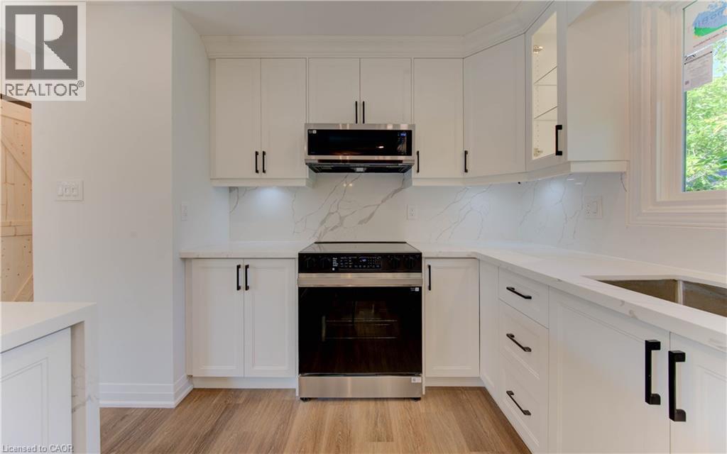 Kitchen featuring range with electric cooktop, glass insert cabinets, backsplash, and light wood finished floors - 90 Culpepper Drive, Waterloo, ON - Indoor Photo Showing Kitchen