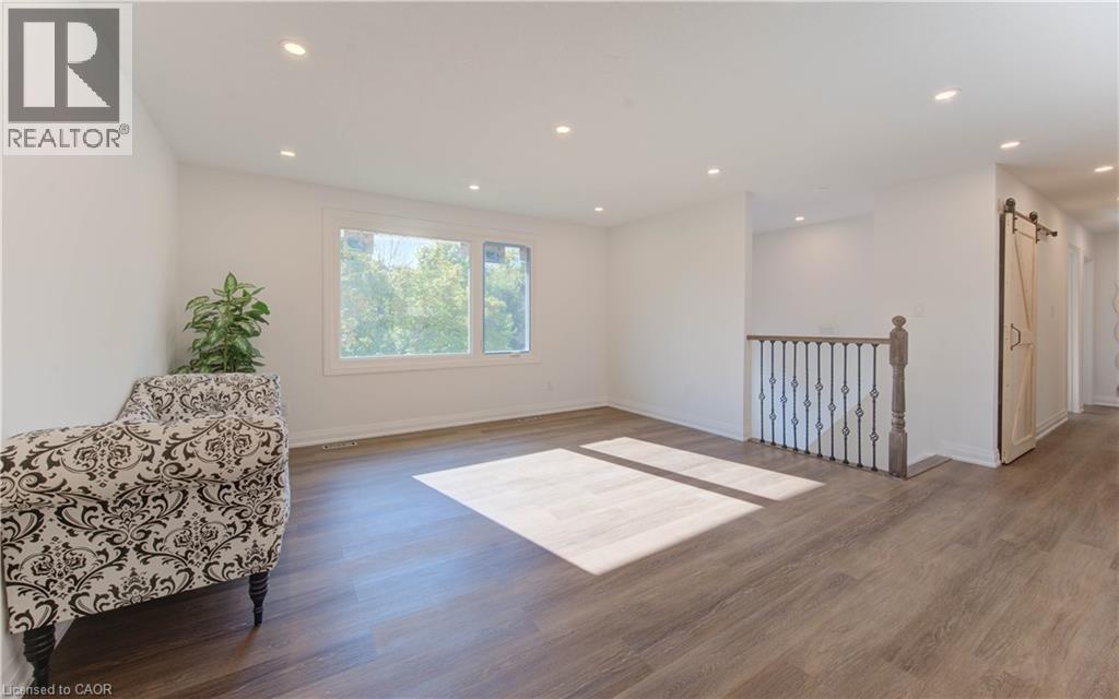 Living area with a barn door, wood finished floors, recessed lighting, and an upstairs landing - 90 Culpepper Drive, Waterloo, ON - Indoor Photo Showing Other Room