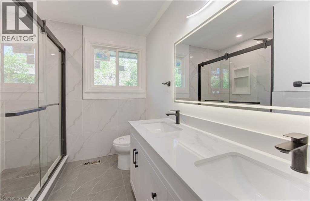Full bath featuring double vanity, a marble finish shower, recessed lighting, and tile walls - 90 Culpepper Drive, Waterloo, ON - Indoor Photo Showing Bathroom