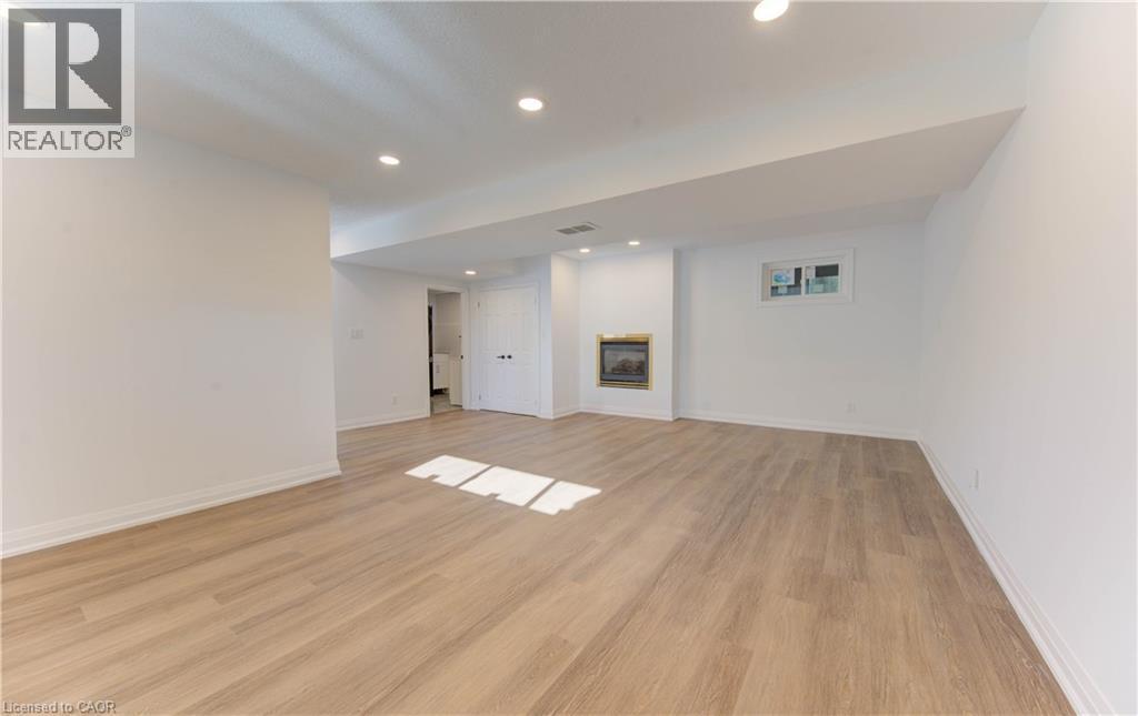 Finished below grade area featuring recessed lighting, light wood-style flooring, and a glass covered fireplace - 90 Culpepper Drive, Waterloo, ON - Indoor Photo Showing Other Room