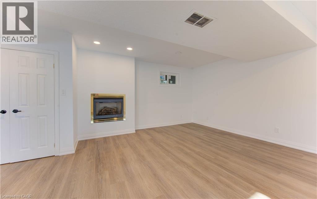 Unfurnished living room featuring a glass covered fireplace, recessed lighting, and light wood-style flooring - 90 Culpepper Drive, Waterloo, ON - Indoor Photo Showing Other Room With Fireplace