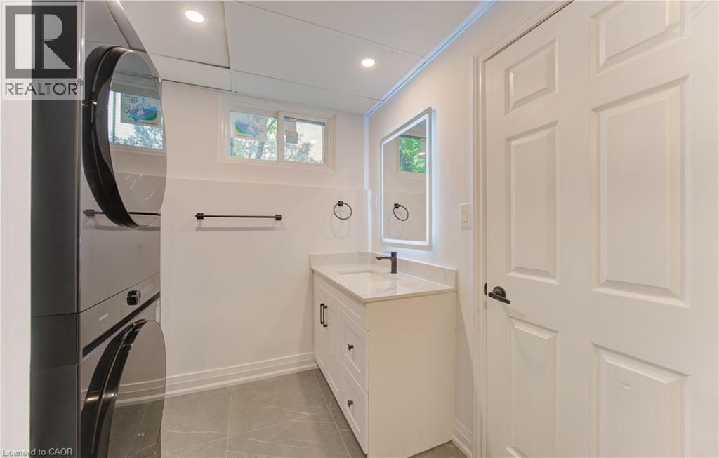 Bathroom with vanity, light tile patterned floors, stacked washer and clothes dryer, recessed lighting, and ornamental molding - 90 Culpepper Drive, Waterloo, ON - Indoor Photo Showing Laundry Room