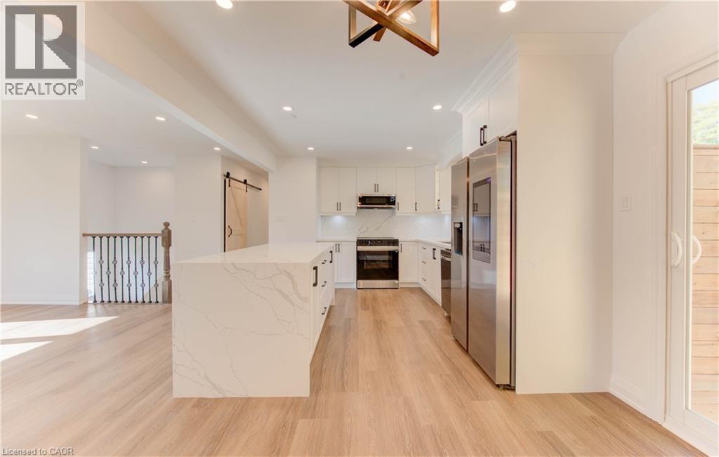 Kitchen with a barn door, white cabinets, stainless steel appliances, recessed lighting, and light wood-style flooring - 90 Culpepper Drive, Waterloo, ON - Indoor Photo Showing Kitchen