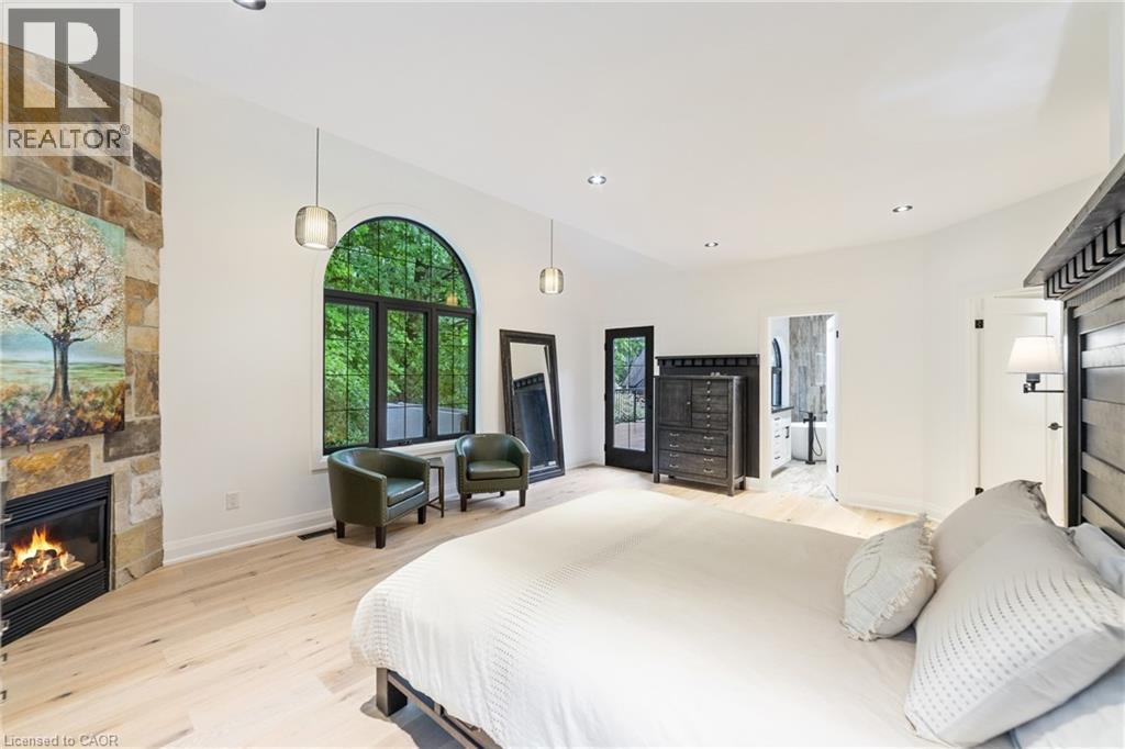 Gas fireplace, luxury flooring, large windows overlooking greenspace, recessed lighting, walk-out to back deck with hot tub - 515 Hamilton Drive, Ancaster, ON - Indoor Photo Showing Bedroom With Fireplace