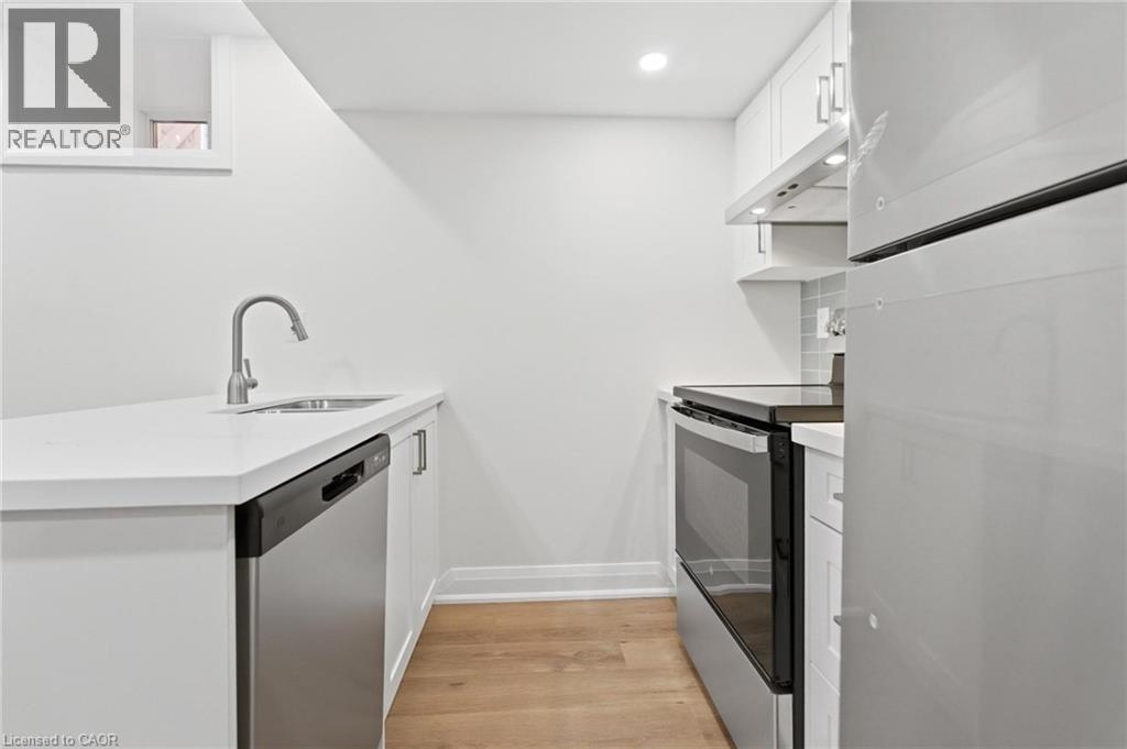 Kitchen featuring a peninsula, stainless steel appliances, white cabinets, light wood finished floors, and recessed lighting - 187 Oak Avenue Unit# Lower, Hamilton, ON - Indoor Photo Showing Kitchen