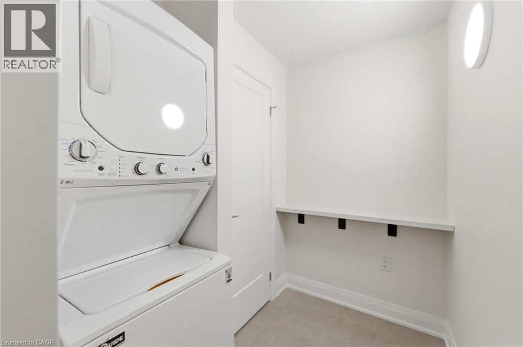 Laundry room with baseboards and stacked washing machine and dryer - 187 Oak Avenue Unit# Lower, Hamilton, ON - Indoor Photo Showing Laundry Room