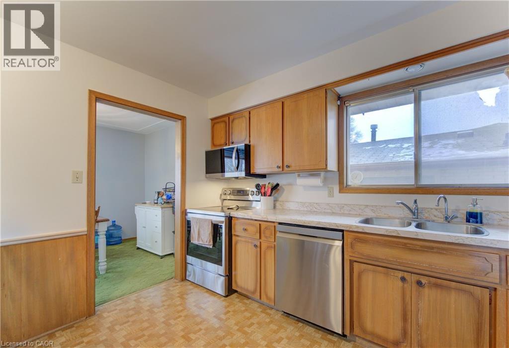 Kitchen with stainless steel appliances, light countertops, wainscoting, wood walls, and parquet flooring - 98 Shea Crescent, Kitchener, ON - Indoor Photo Showing Kitchen With Double Sink