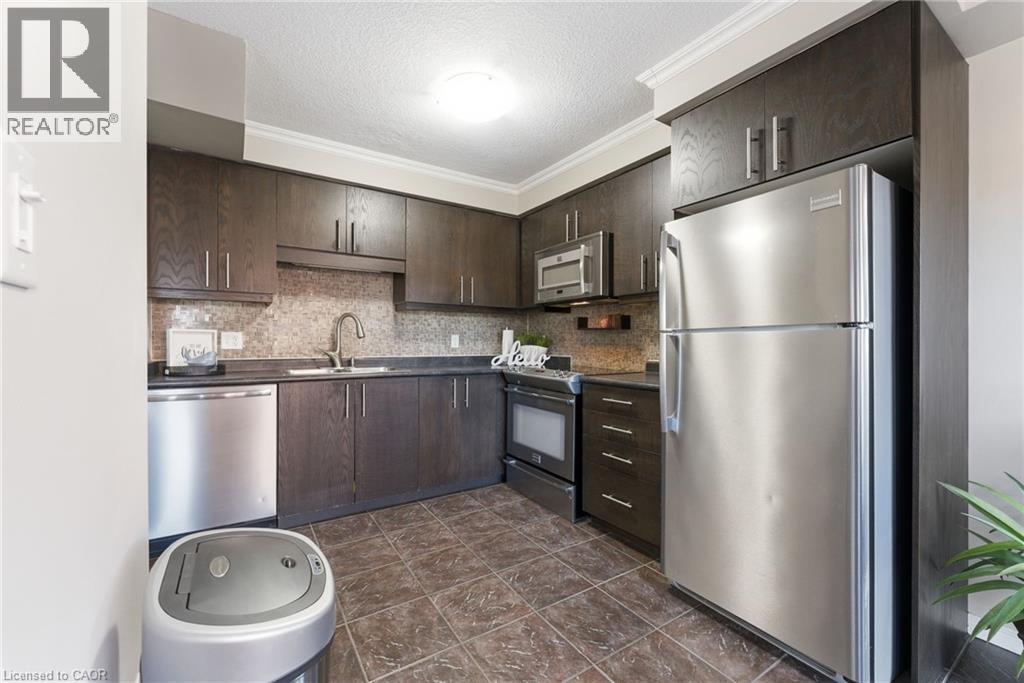 Kitchen featuring dark wood finish cabinetry, stainless steel appliances, dark countertops, a textured ceiling, and tasteful backsplash - 208 Templewood Drive, Kitchener, ON - Indoor Photo Showing Kitchen With Stainless Steel Kitchen With Upgraded Kitchen
