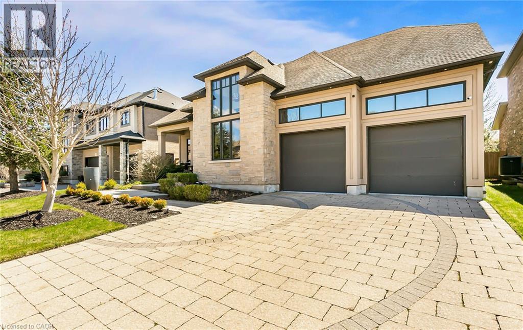 View of front of home featuring driveway, stone siding, a shingled roof, and an attached garage - 24 Jacob Gingrich Drive, Kitchener, ON - Outdoor With Facade