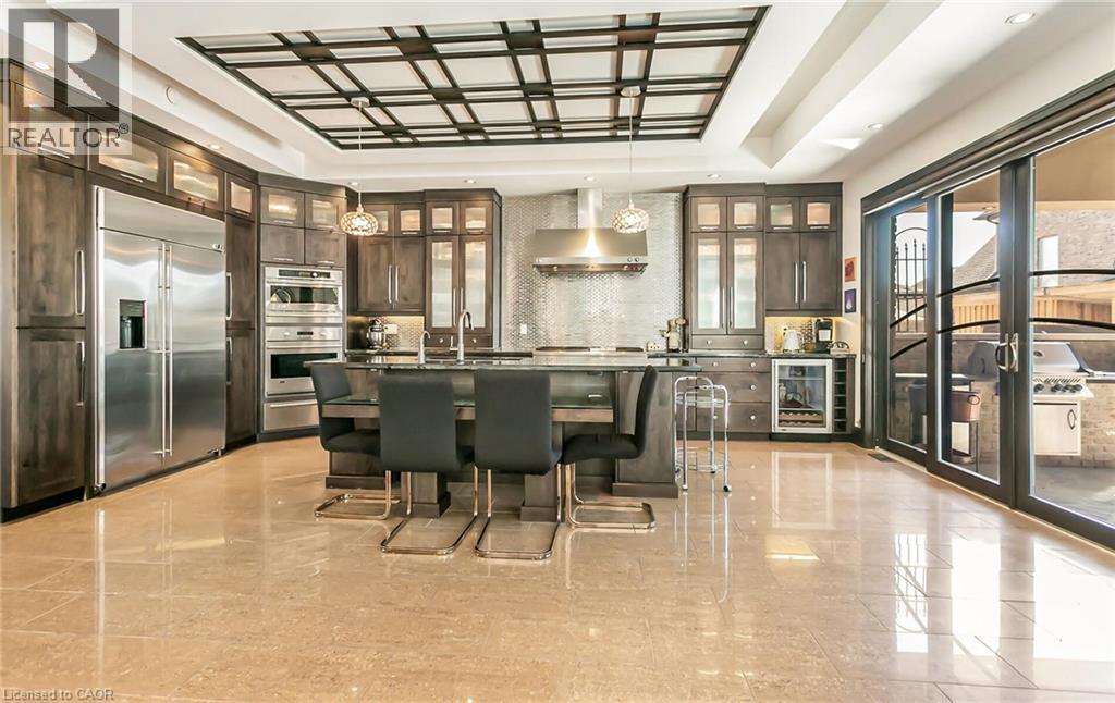 Kitchen with an island with sink, dark wood finish cabinetry, stainless steel appliances, and glass fronted cabinets - 24 Jacob Gingrich Drive, Kitchener, ON - Indoor Photo Showing Dining Room