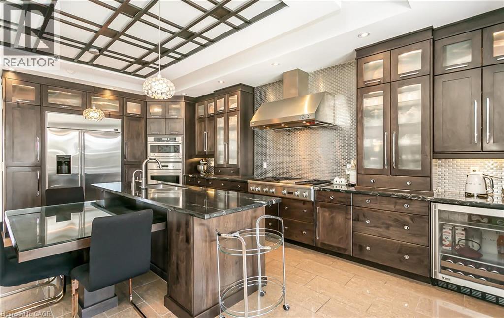 Kitchen featuring wine cooler, dark wood finish cabinetry, a kitchen breakfast bar, a kitchen island with sink, and decorative light fixtures - 24 Jacob Gingrich Drive, Kitchener, ON - Indoor Photo Showing Kitchen With Upgraded Kitchen