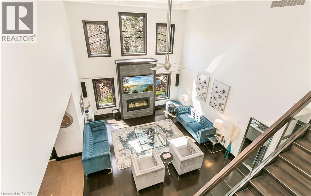 Living area featuring a glass covered fireplace, a high ceiling, ceiling fan, and dark wood finished floors - 24 Jacob Gingrich Drive, Kitchener, ON - Indoor Photo Showing Other Room With Fireplace